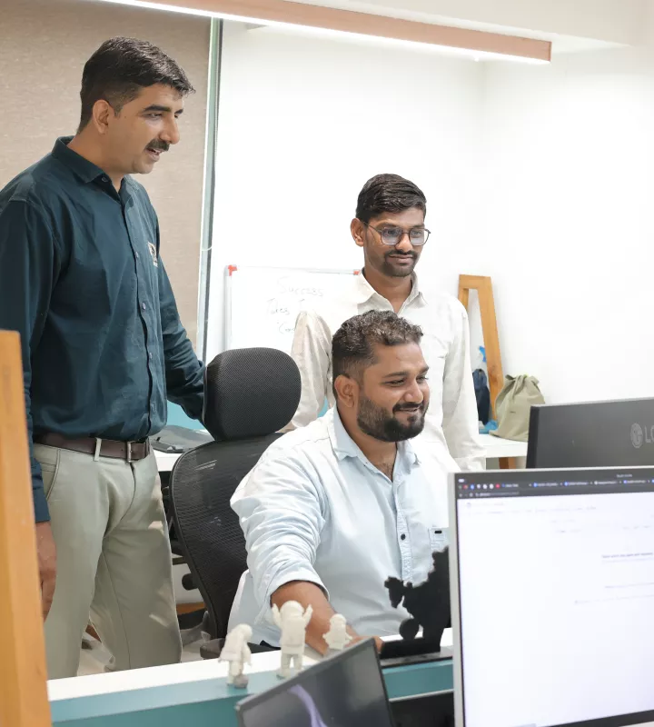 Three colleagues reviewing work together at a desk