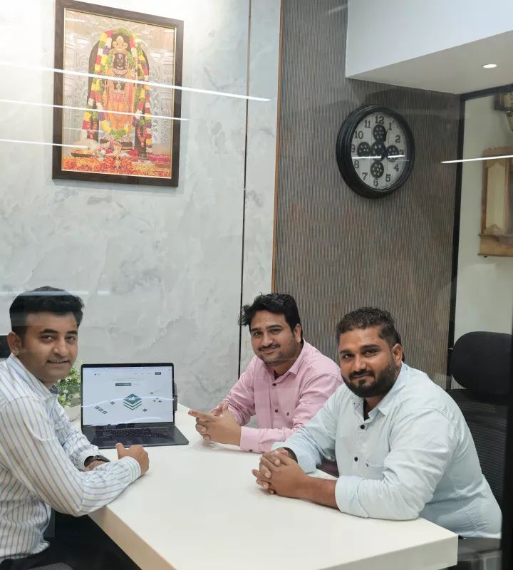 Three team members meeting around a laptop