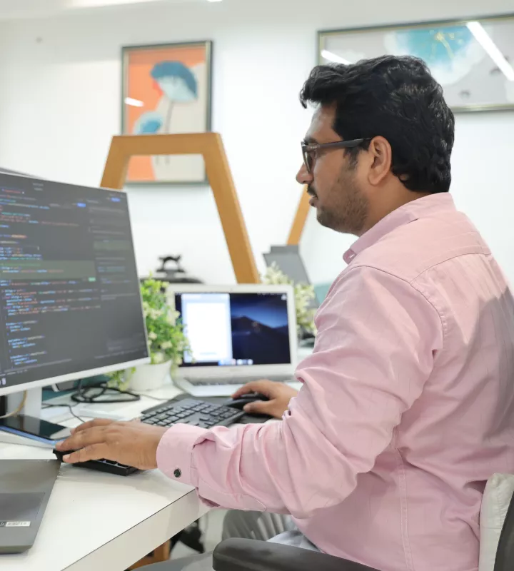 Engineer writing code across a monitor and a laptop
