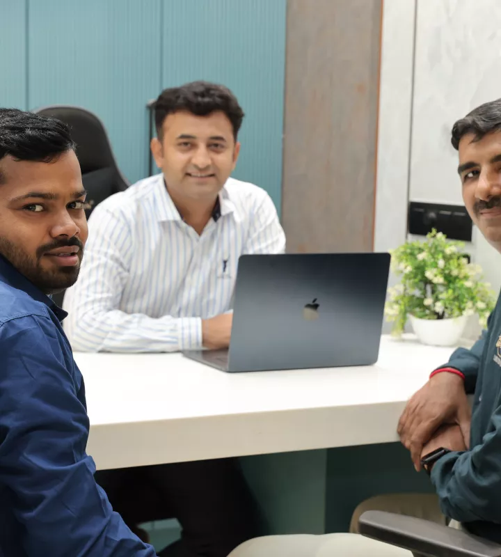 Three colleagues in discussion around a laptop