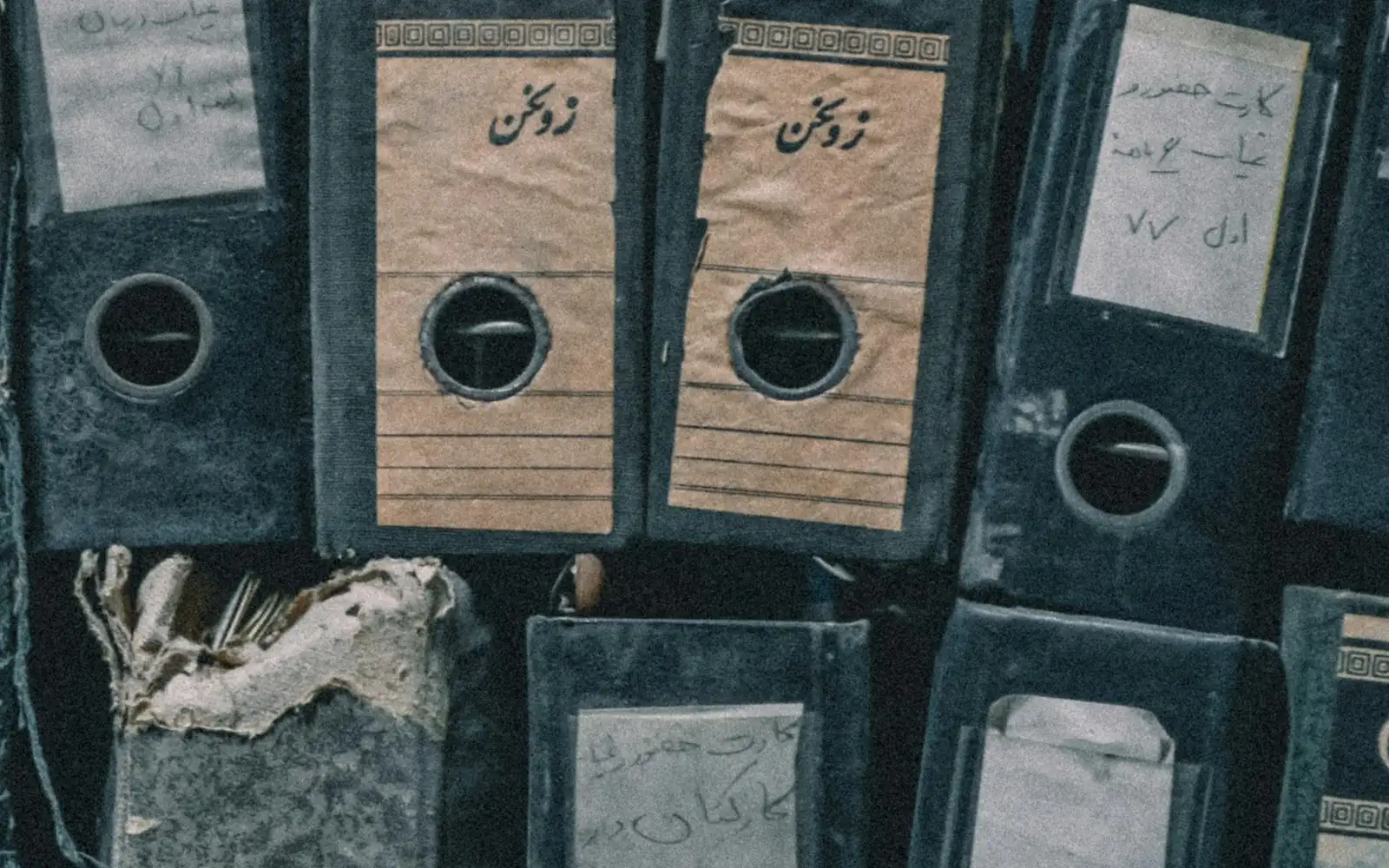 Worn lever-arch files packed tight on a shelf, every spine hand-labelled in ink.